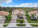 Beautiful two-story home with a tile roof, green lawn and landscaping, and a brick-paved driveway leading to a three-car garage at 8886 Fallen Oak Dr, Davenport, FL 33896