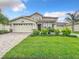 Charming two-story home featuring a lush green lawn, beautiful landscaping, and a brick-paved driveway leading to a three-car garage at 8886 Fallen Oak Dr, Davenport, FL 33896