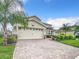 Charming home with a two-car garage, lush landscaping, and a brick paver driveway at 8886 Fallen Oak Dr, Davenport, FL 33896