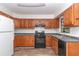 Kitchen with wood cabinets, black appliances, and vinyl flooring at 11431 Nw 100Th St, Ocala, FL 34482