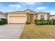 One-story house with a yellow exterior, a two-car garage, and well-manicured landscaping at 841 Greenshank Dr, Haines City, FL 33844