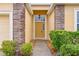 Front entrance with a mustard-yellow door, brick columns and landscaping at 841 Greenshank Dr, Haines City, FL 33844