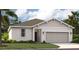 One-story home with light-colored siding, a two-car garage, and a well-manicured lawn at 9544 Starling Loop, Leesburg, FL 34788