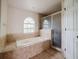 Bathroom with a soaking tub, tiled shower, and arched window at 1010 Embrun Ct, Kissimmee, FL 34759