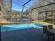 Screened-in pool with patio furniture and pond view at 13029 Cog Hill Way, Orlando, FL 32828