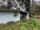 Light blue house exterior with overgrown landscaping at 1504 Laun Pl, Lakeland, FL 33803