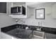 Modern wet bar with microwave, sink, and granite countertop at 1549 Corolla Ct, Reunion, FL 34747
