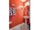 Small half-bathroom with pedestal sink and orange walls at 16583 Cedar Crest Dr, Orlando, FL 32828