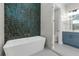 Stylish bathroom featuring a soaking tub, green tile wall, and blue vanity at 2510 Amherst Ave, Orlando, FL 32804