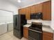 Kitchen with wood cabinets, black appliances, and adjacent laundry area at 3300 Whitestone Cir # 101, Kissimmee, FL 34741