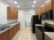 Modern kitchen featuring wood cabinets, black appliances, and tile floor at 3300 Whitestone Cir # 101, Kissimmee, FL 34741