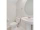 Small bathroom with pedestal sink, toilet and oval mirror at 33339 Seattle Slew Dr, Sorrento, FL 32776