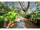 Landscaped backyard with a path, lush greenery, and a large oak tree at 506 N Dillard St, Winter Garden, FL 34787