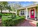 Bright pink door entrance with brick walkway, lush landscaping, and a beautiful lawn at 506 N Dillard St, Winter Garden, FL 34787