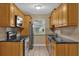 Galley-style kitchen with wood cabinets, granite countertops, and stainless steel appliances at 107 Japonica Dr, Orlando, FL 32807