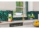 Close-up of a kitchen sink, faucet, and green herringbone tile backsplash at 222 Flame Ave, Maitland, FL 32751