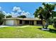 Tan house with white garage door, palm tree, and landscaped lawn at 620 Heraldo Ct, Kissimmee, FL 34758
