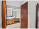 Hallway view of bathroom vanity with warm cabinets and a mirror; bedroom visible in the mirror at 654 Boniview Ln, Altamonte Springs, FL 32714