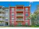 Three-story building with red exterior, balconies, and lush landscaping at 1410 Celebration Ave # 101, Celebration, FL 34747