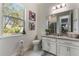 Bathroom with granite vanity, large mirror, and window overlooking backyard at 16669 Varone Cove Ct, Winter Garden, FL 34787