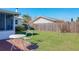 A brick patio with table and chairs overlooks the spacious backyard with a wood fence under a clear blue sky at 2207 Winter Woods Blvd, Winter Park, FL 32792