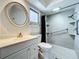 Well-lit bathroom featuring a single sink vanity, toilet, and tiled shower with handrails at 2207 Winter Woods Blvd, Winter Park, FL 32792