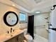 Well-lit bathroom featuring a round mirror, skylight and tiled walk-in shower with safety bars at 2207 Winter Woods Blvd, Winter Park, FL 32792