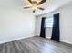 Bedroom with wood-look flooring, ceiling fan, and a large window with dark curtains at 2207 Winter Woods Blvd, Winter Park, FL 32792