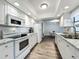 Bright kitchen with granite countertops, white appliances, and modern wood-look flooring at 2207 Winter Woods Blvd, Winter Park, FL 32792