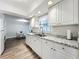 Well-lit kitchen featuring granite countertops, white cabinets, stainless steel sink, and wood-look flooring at 2207 Winter Woods Blvd, Winter Park, FL 32792