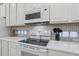 White kitchen features cooktop, microwave, and stylish backsplash at 2628 Calistoga Ave, Kissimmee, FL 34741