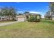 Front view of a one-story house with a beige garage door and lush green lawn at 2711 Angel Mist Ct, Mascotte, FL 34753