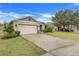 Landscaped one-story house with a beige garage door and a spacious driveway at 2711 Angel Mist Ct, Mascotte, FL 34753