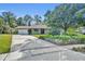 Inviting single-story home with a brick facade, an ample driveway, mature landscaping, and blue shutters at 4130 Floralwood Ct, Orlando, FL 32812