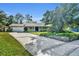 Inviting single-story home with a brick facade, an ample driveway, mature landscaping, and blue shutters at 4130 Floralwood Ct, Orlando, FL 32812