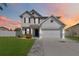 Two-story house with gray exterior, two-car garage, and landscaped lawn at sunset at 131 Cambria Grove Cir, Davenport, FL 33837