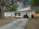 Tan house with blue door, white shutters, and a large tree in the front yard at 1404 Adair St, Ocoee, FL 34761