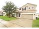 Two-story house with beige siding, brown roof, and a two-car garage at 15269 Galbi Dr, Orlando, FL 32828