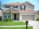 Two-story house with beige siding, brown roof, and a two-car garage at 15269 Galbi Dr, Orlando, FL 32828