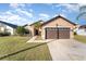Tan house with brown double garage door and green lawn at 2463 Hybrid Dr, Kissimmee, FL 34758
