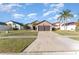 Tan house with brown double garage door, green lawn, and palm trees at 2463 Hybrid Dr, Kissimmee, FL 34758