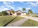 Tan house with brown double garage door, green lawn, and palm trees at 2463 Hybrid Dr, Kissimmee, FL 34758