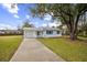 White house with blue accents, driveway, and large tree in the front yard at 277 Debary Dr, Debary, FL 32713