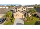 Two-story house with beige exterior, two-car garage, and landscaped yard at 3019 Madelia Ln, Kissimmee, FL 34744