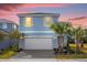 Two-story light blue house with a white garage door and landscaping at 7260 Oakmoss Loop, Davenport, FL 33837