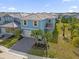 Two-story light blue house with gray roof and palm trees at 7260 Oakmoss Loop, Davenport, FL 33837