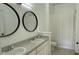 Bright bathroom featuring double sinks, round mirrors, and a shower with patterned curtain at 8634 Danforth Dr, Windermere, FL 34786