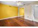 Bedroom with wood floors, mirrored closet doors, and yellow accent wall at 1018 Bear Lake Rd, Apopka, FL 32703