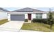 One-story house with gray garage door and solar panels at 1623 Aspen Ave, Davenport, FL 33837