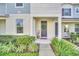 Townhome's front entrance with gray door, wreath, and well-manicured landscaping at 2102 Gopher Tortoise Ter, Oakland, FL 34787